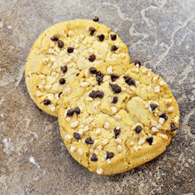 Load image into Gallery viewer, Two cookies with chocolate chips and toffee bits on a stone surface