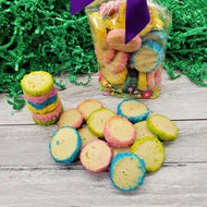 Colorful round cookies on a wooden surface with a bag of cookies in the background.