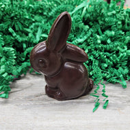 Chocolate rabbit on a wooden surface with green decorative grass in the background