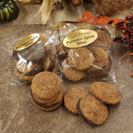Packaged pumpkin spice cookie bites with dark chocolate topping and cinnamon sugar on a decorative surface with autumn leaves around.