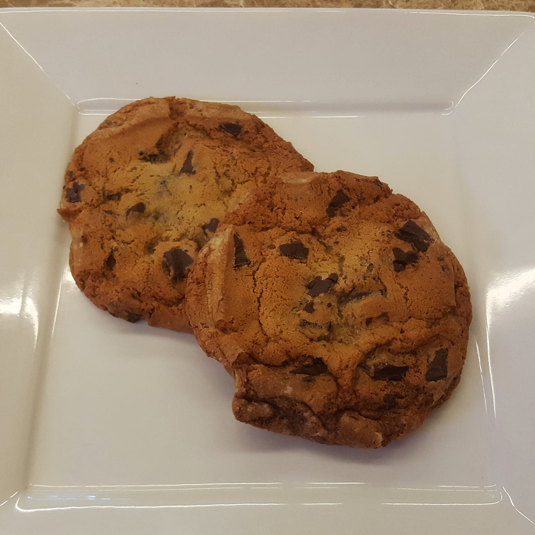 Two chocolate chip cookies on a white plate. 